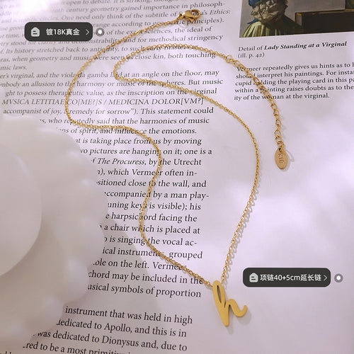 Gold letter H necklace flat lay with plating and length labels