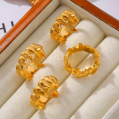 Four gold flame-spike rings on cream jewelry tray