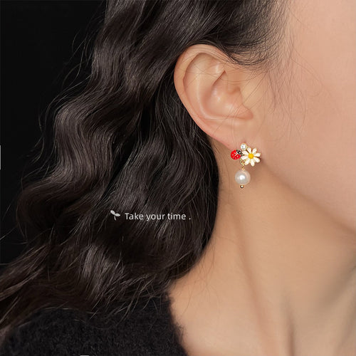 Daisy ladybug pearl earring worn on ear with dark hair