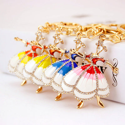 Four dancing girl keychains with red, yellow, blue, and white dress details are displayed together.