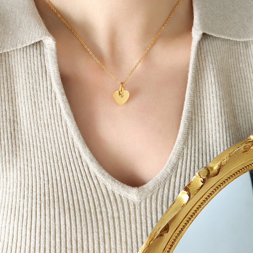 Gold hollow heart pendant necklace worn on beige top