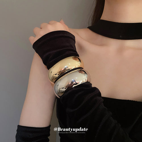 polished gold-tone and silver-tone wide oval bangles stacked on a wrist