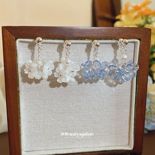 Product close-up of 白蓝花簇垂坠耳环 showing round clusters of small translucent flowers in white or pale blue beneath pearl-lik