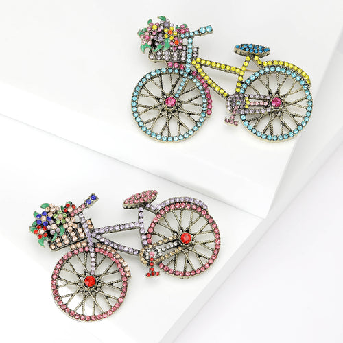Front view of the crystal bicycle brooch in blue or pink with polished metal detail on a white background