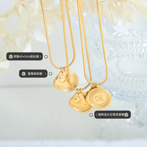 Several gold R seal and moon pendants hanging with length labels