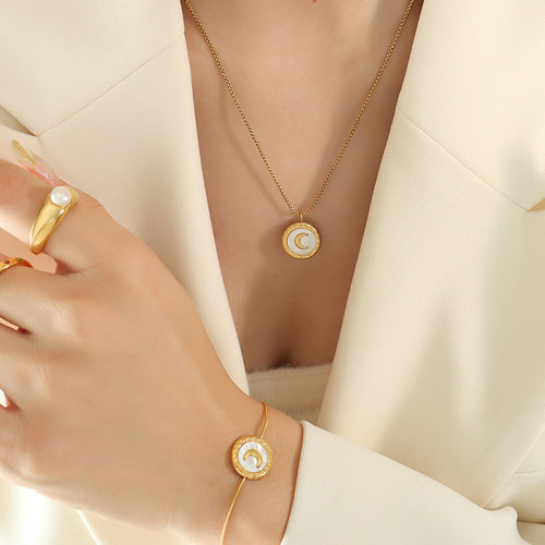 Gold pearl crescent moon necklace and matching bracelet worn with cream blazer