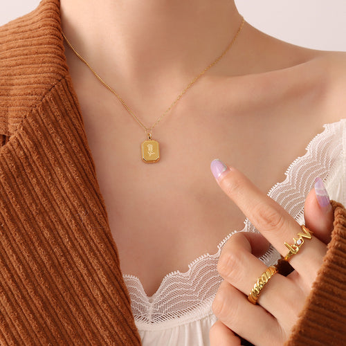 Gold rose square tag pendant necklace worn with brown corduroy jacket