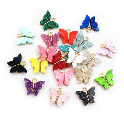 Assorted colorful upright butterfly charms with glittered wings arranged together on a plain background