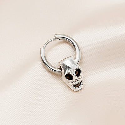 Silver huggie hoop with open-eye grinning skull charm on pink satin
