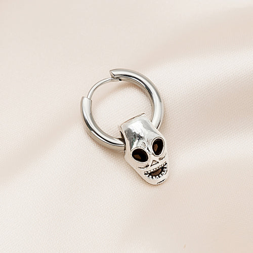 Silver huggie hoop with open-eye grinning skull charm on pink satin