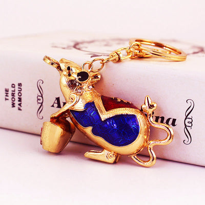 Angled view of a gold-tone mouse holding an acorn with blue and red body details.