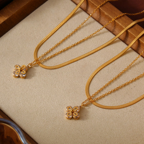 Two gold double-layer snake and cable flower pendant necklaces on tray