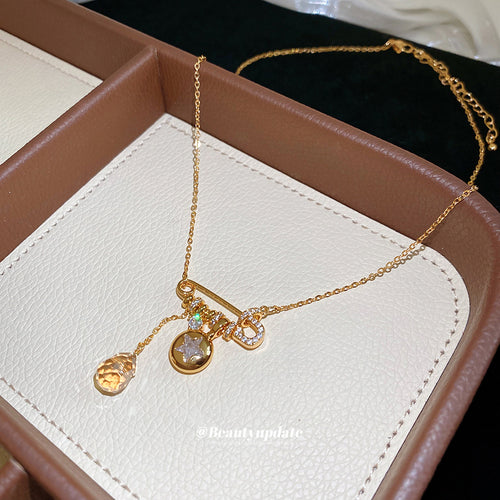 Close display of a horizontal pin-style bar carrying small colored accents, a round crystal, and a teardrop charm