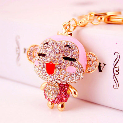Close-up of a pink rhinestone monkey keychain with a winking face.