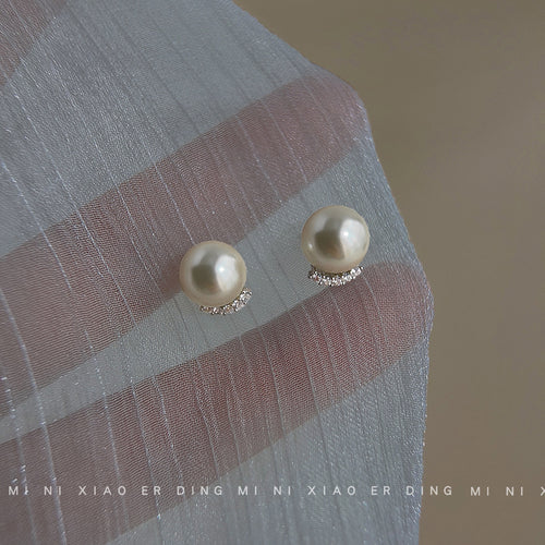 Pearl crescent pavé studs held against sheer gray fabric