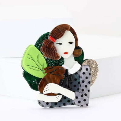 A girl holding a gray spotted rabbit against green leaves shown on a white background
