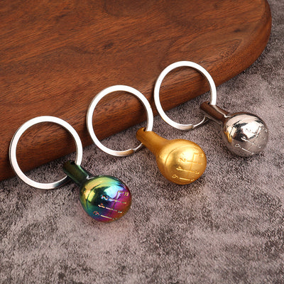 Three miniature gear shift knob keychains in multicolor, gold, and silver finishes.