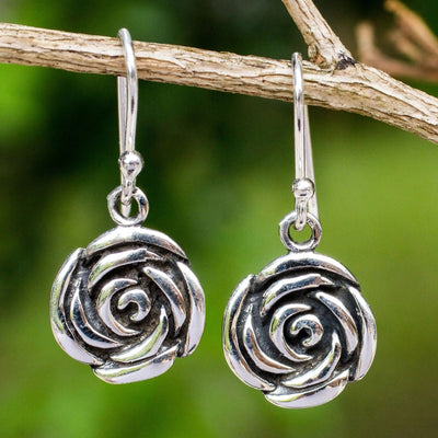 Antique silver rose drop earrings hanging from thin outdoor branch