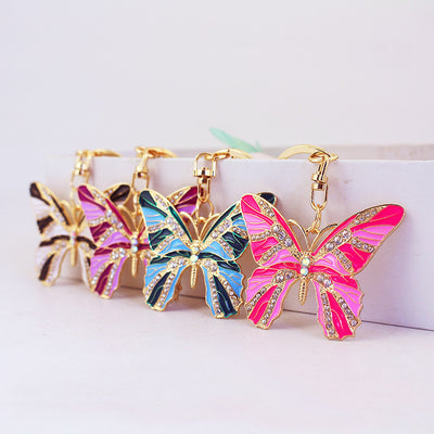 Four colorful butterfly keychains displayed in pink, blue, purple, and black-and-white designs.