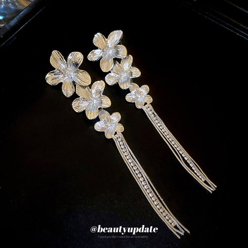 Styled close-up of silver-tone floral crystal tassel earrings