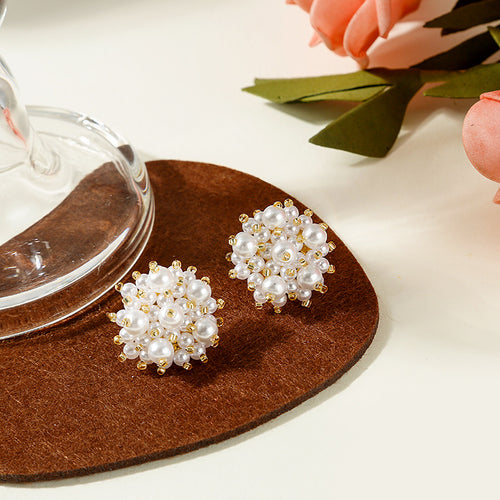White pearl gold-accent cluster studs on brown heart-shaped pad