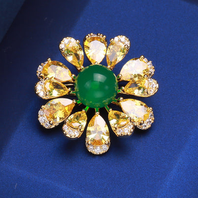 Front view of yellow teardrop-petal daisy brooch with green round center against a white background.