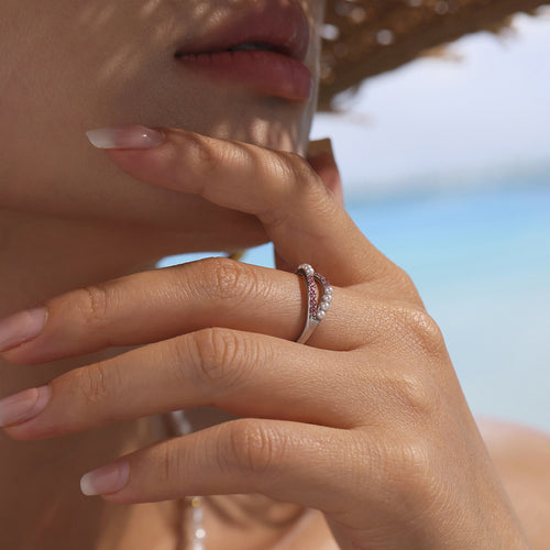 Model wearing steel open ring with pink zircon and shell beads outdoors