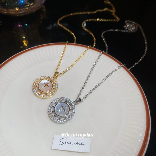 A round openwork medallion with a cross-like crystal motif on a fine chain shown in a styled close-up
