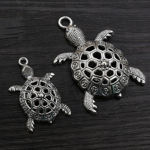 Finish comparison of openwork turtle shaped metal charms in two pictured sizes
