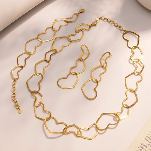 Gold open-heart necklace bracelet and triple-heart earrings on soft fabric