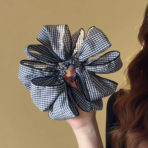 Hand holding fully open black white gingham bow scrunchie