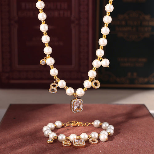 Matching gold pearl necklace and bracelet on velvet with books