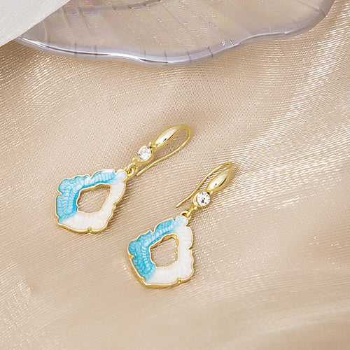 Blue white geometric enamel earrings on champagne fabric