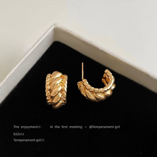 Gold twisted braided C hoop studs in black jewelry box corner