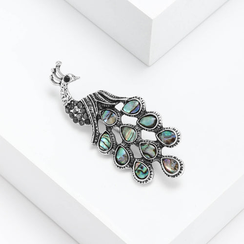 Angled silver peacock brooch showing iridescent shell inlays