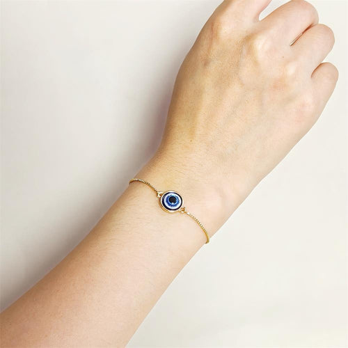 Gold evil eye bracelet worn on wrist showing blue eye center charm
