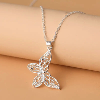 Silver filigree butterfly pendant necklace draped on beige cylinder