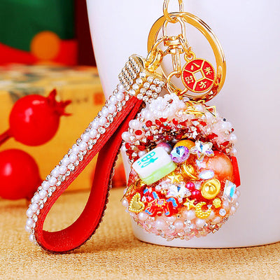 A styled front view shows the crystal-filled treasure bowl keychain and its attached hardware.