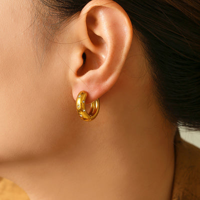 Model wearing gold star rhinestone huggie hoop earring