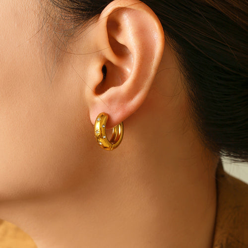 Model wearing gold star rhinestone huggie hoop earring