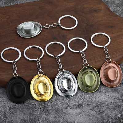 Six hat-shaped keychains in black, gold, two silver tones, olive bronze tone, and copper tone are displayed together.