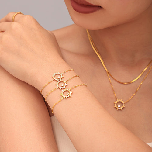 Wrist with three gold sunburst zircon bracelets and matching necklace