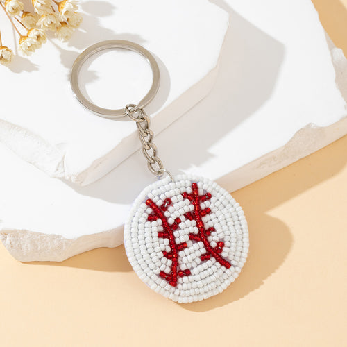 White and red beaded baseball stitch keychain on a marble slab with dried flowers
