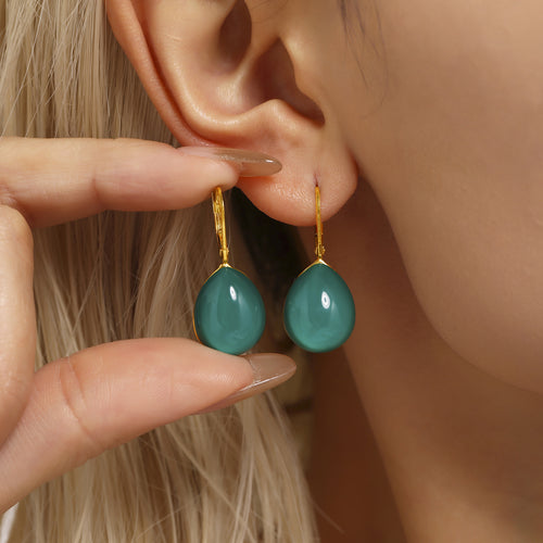 Model holding teal green resin teardrop leverback earrings