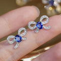 White Metal Bow Stud Earrings Blue Oval Center Pavé Stones view 2