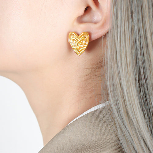 Model ear wearing gold nested ribbed heart stud earring