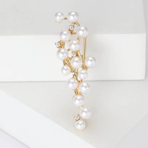 A slim branching vine dotted with white pearls and crystals shown in a styled display.