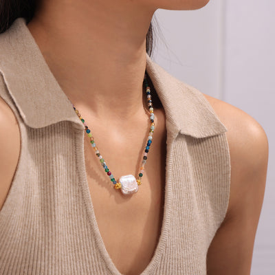 Multicolor stone bead necklace with large baroque pearl worn on collarbone