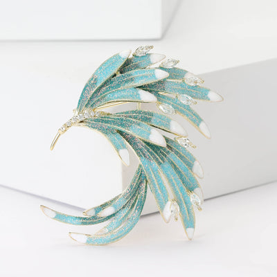 Turquoise enamel phoenix feather brooch angled on white blocks