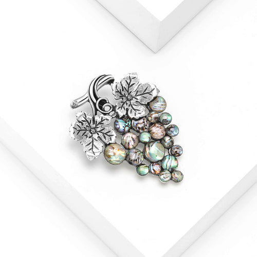 Angled display of grape cluster formed from iridescent round inlays beneath textured leaves